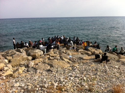 Un gruppo di migranti sugli scogli